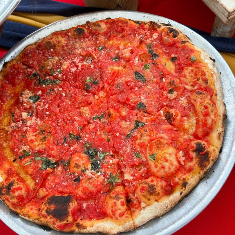 A whole Marco Pizzeria marinara pizza, topped with rich red sauce, basil, and grated cheese.