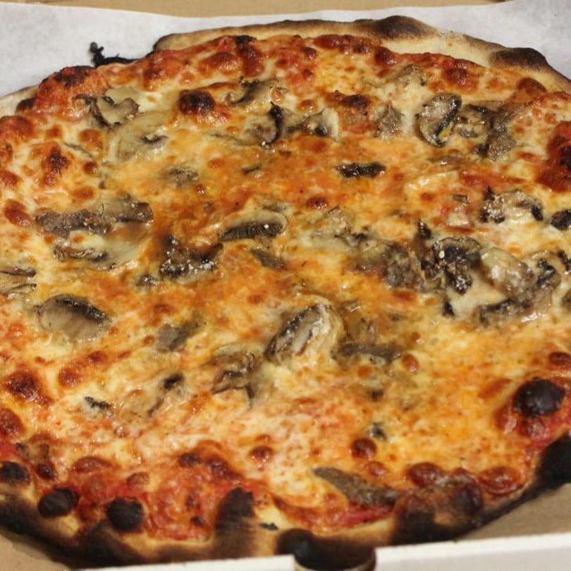 Marco Pizzeria's mushroom pizza, featuring a golden-brown crust, melted cheese, and sliced mushrooms.