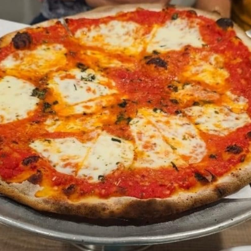 A whole Marco Pizzeria Margherita pizza with fresh mozzarella, tomato sauce, and basil on a metal tray.