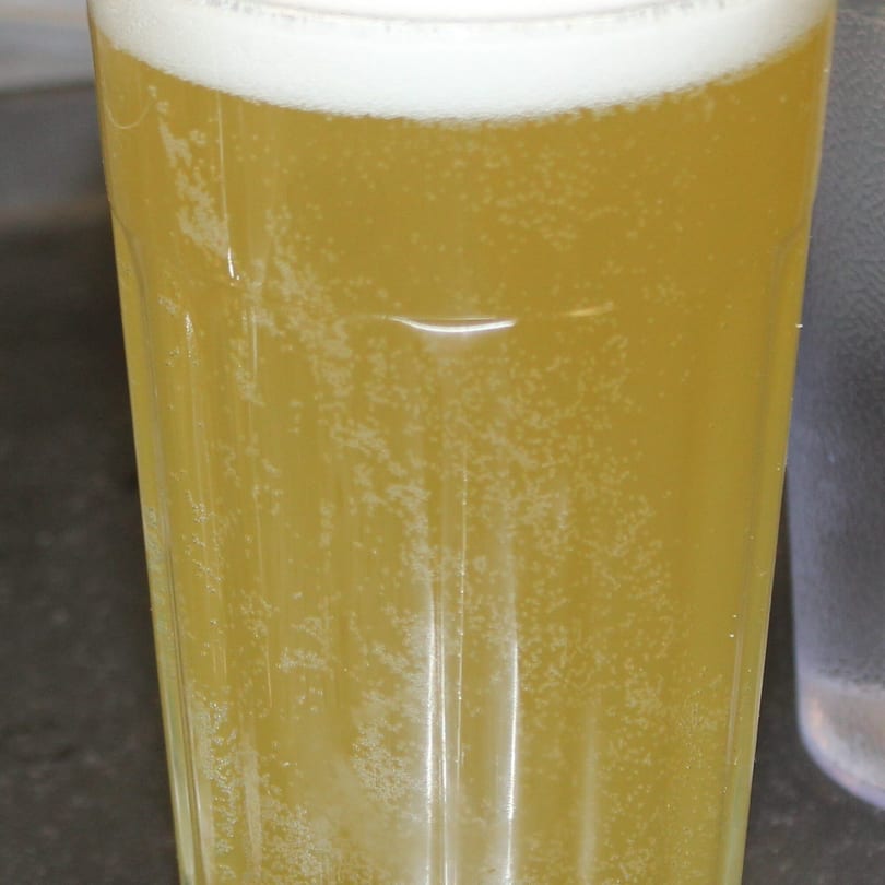 Close-up of a glass of golden beer with a foamy head and visible bubbles.