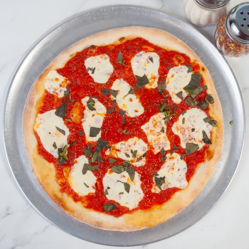 Marco Pizzeria's Margherita pizza with fresh mozzarella, basil, and tomato sauce on a metal tray.