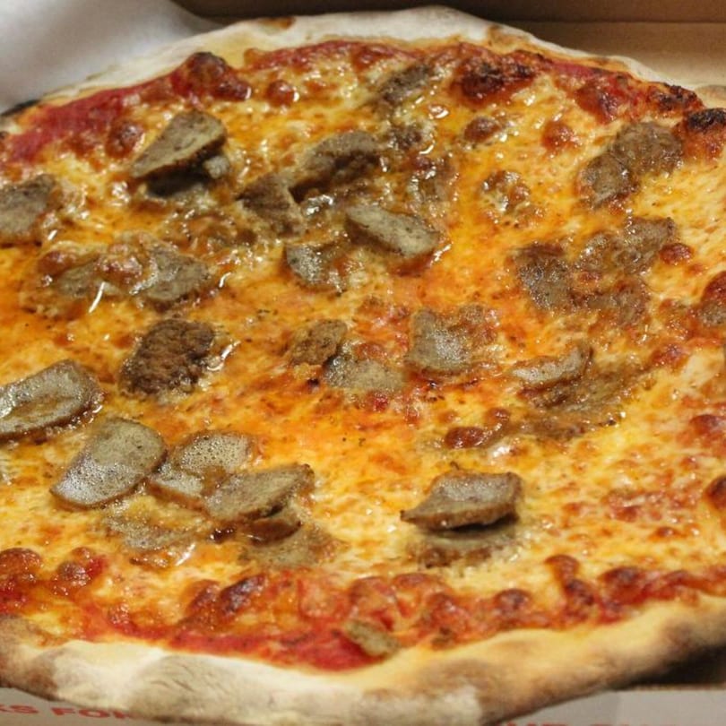 Close-up of a Marco Pizzeria Italian sausage pizza with melted cheese and tomato sauce.