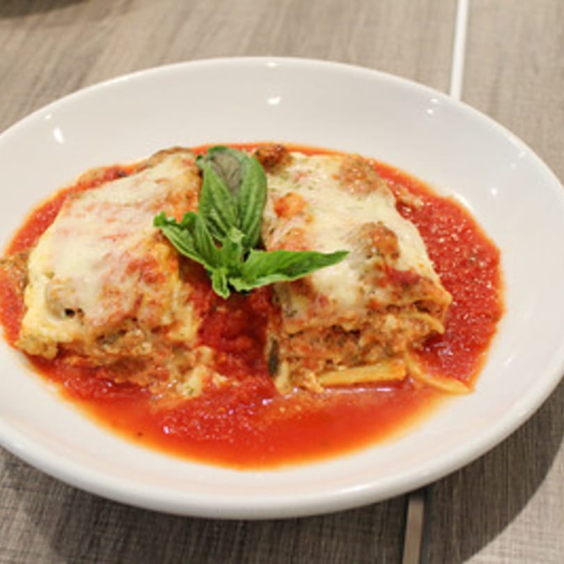 Two servings of Marco Pizzeria's lasagna with melted cheese, tomato sauce, and fresh basil.